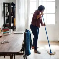 Woman mopping floors next to a table
