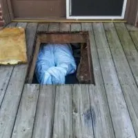 Person in s hazmat jumpsuit in the crawlspace under a house