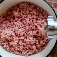 overhead view of fresh ground turkey in a bowl with a meat grinder off to one side