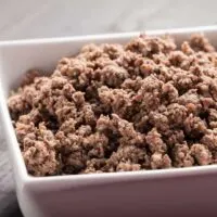 Square bowl full of browned ground meat