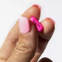 Close up of fingers holding a Benadryl tablet